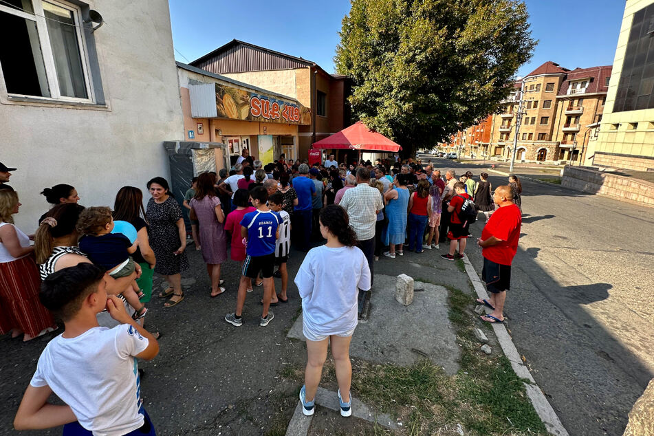 Menschen stehen vor einer Bäckerei in Stepanakert um Brot an.